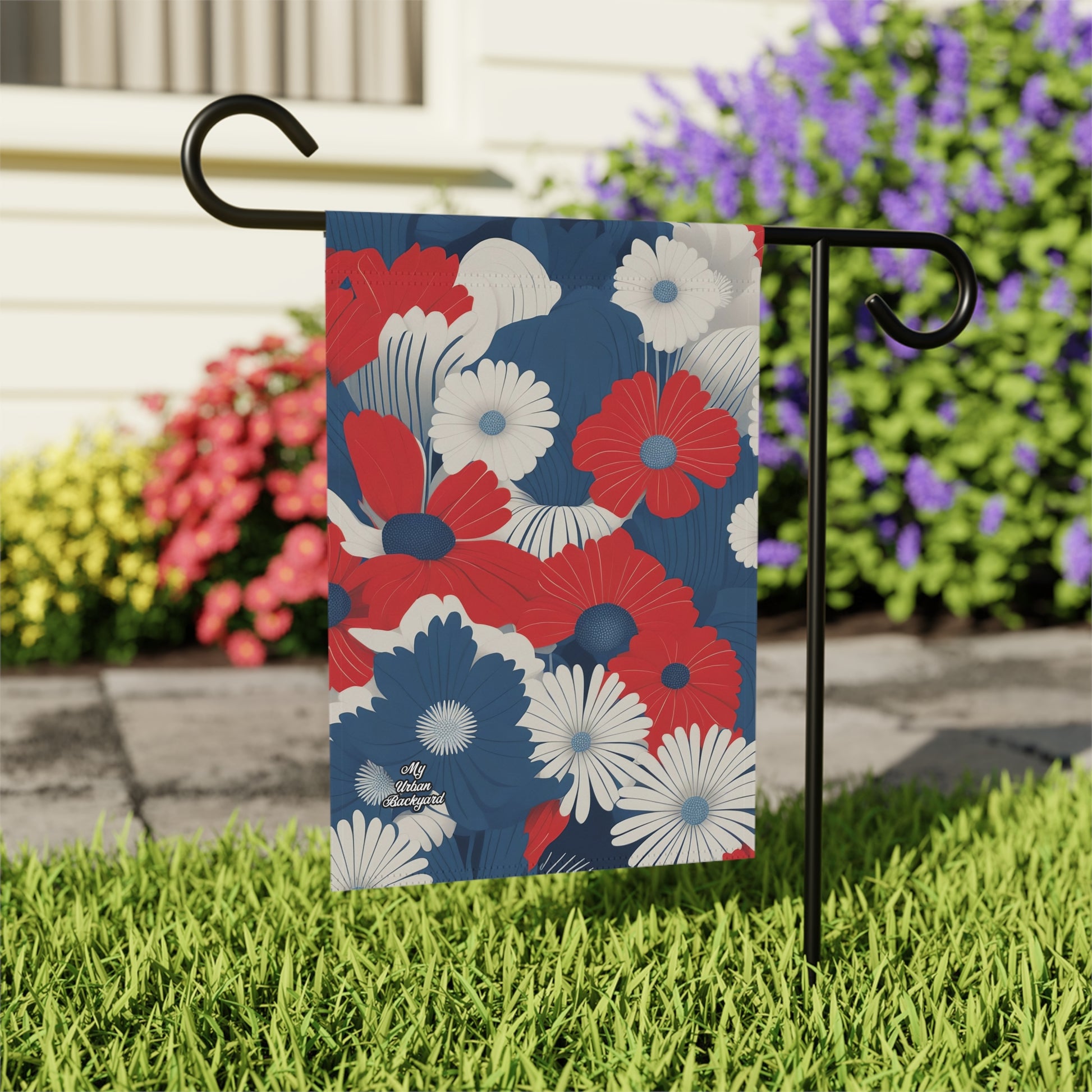 Floral garden flag with red, white, and blue flowers on a stand in front of a house with flowers.